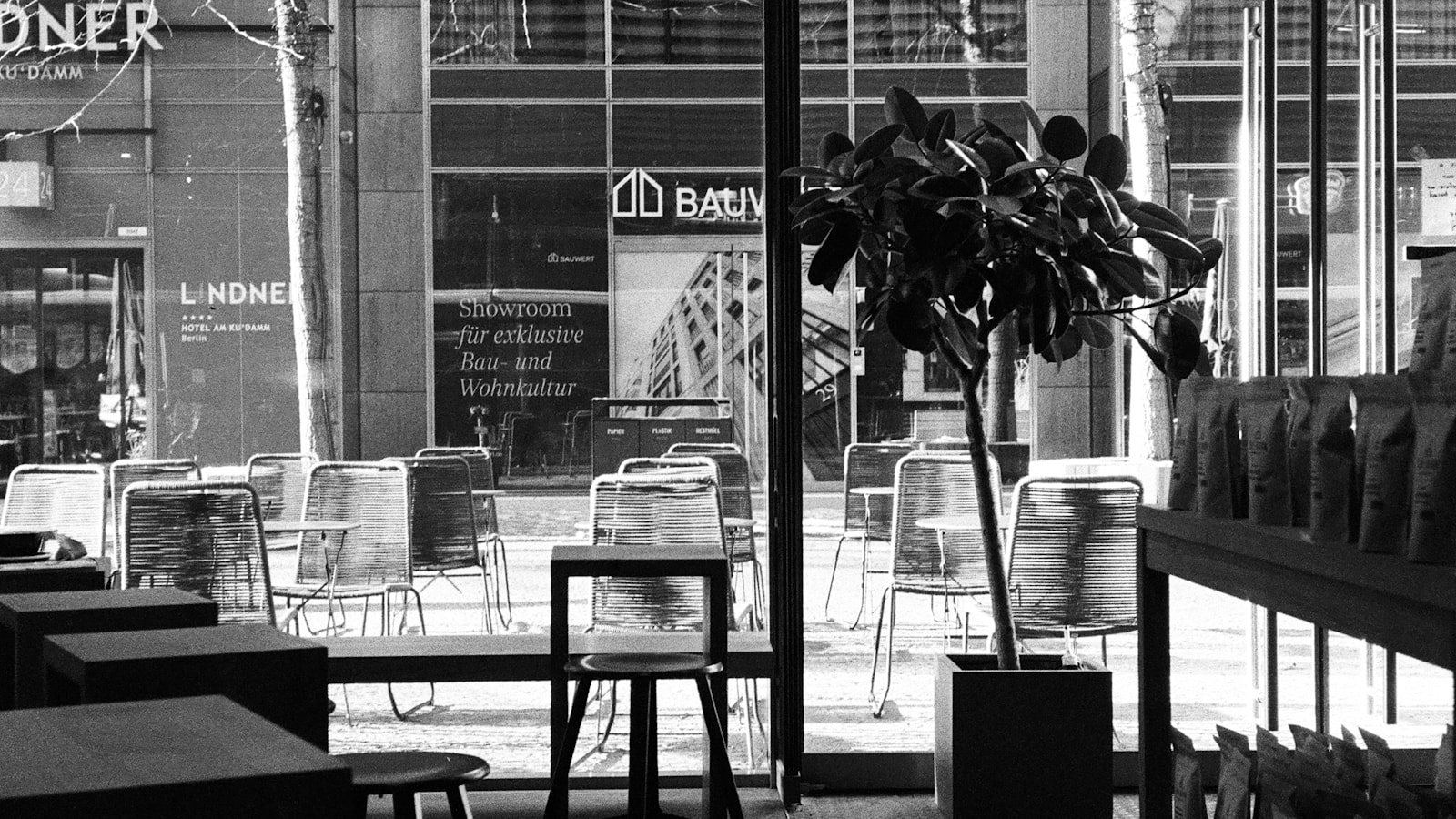 Schwarzweißaufnahme eines Berliner Cafés mit Blick durch die Fenster auf die Straße.