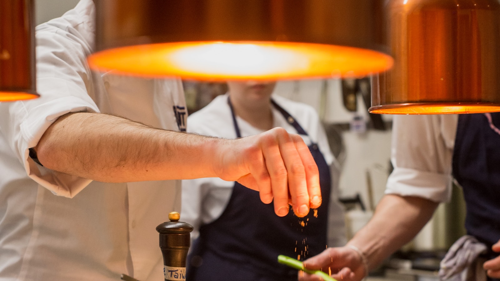 Ein Koch richtet unter den Wärmelampen einer Restaurantküche Speisen an.